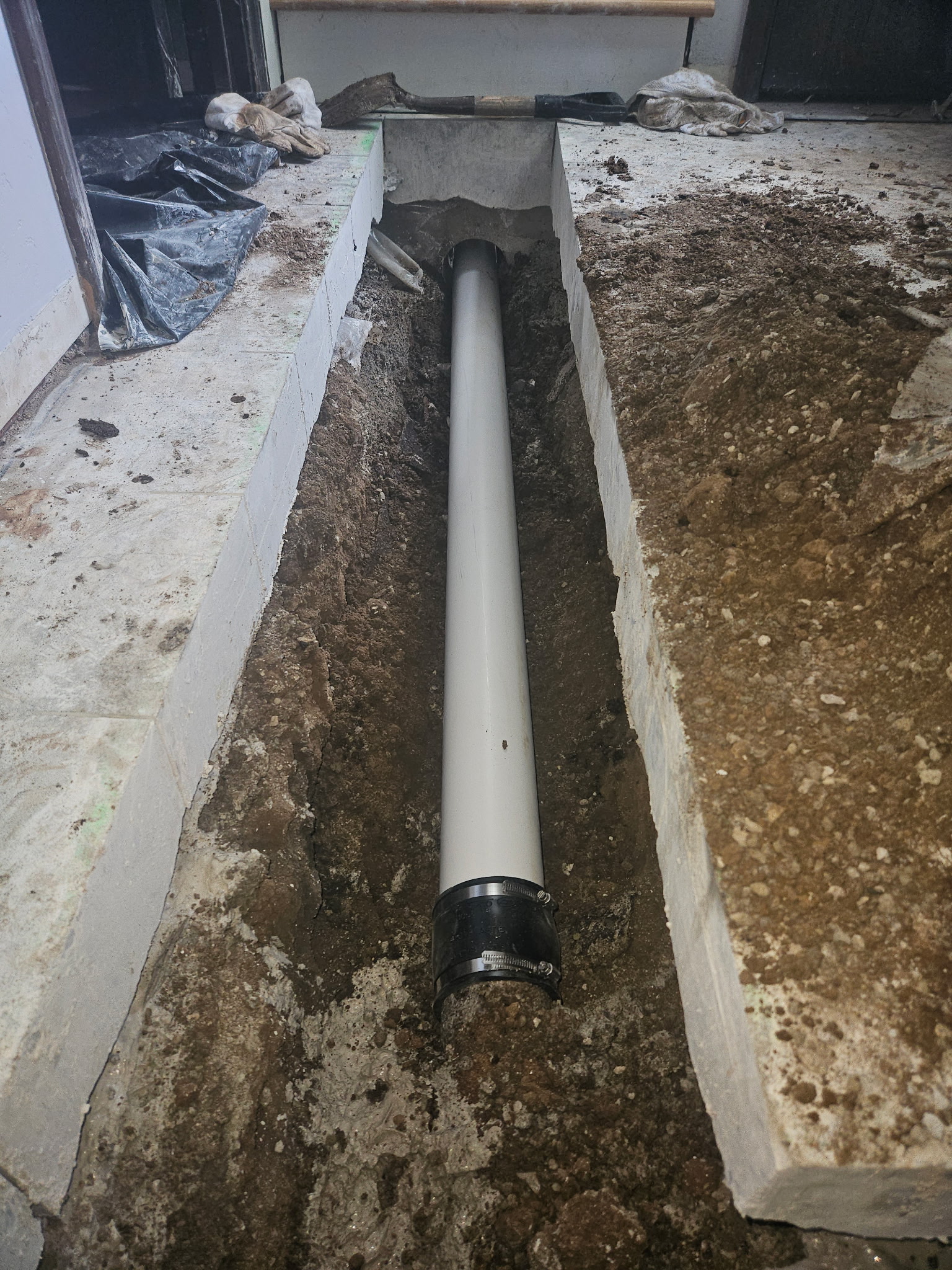 New PVC drain pipe installed beneath an interior concrete floor