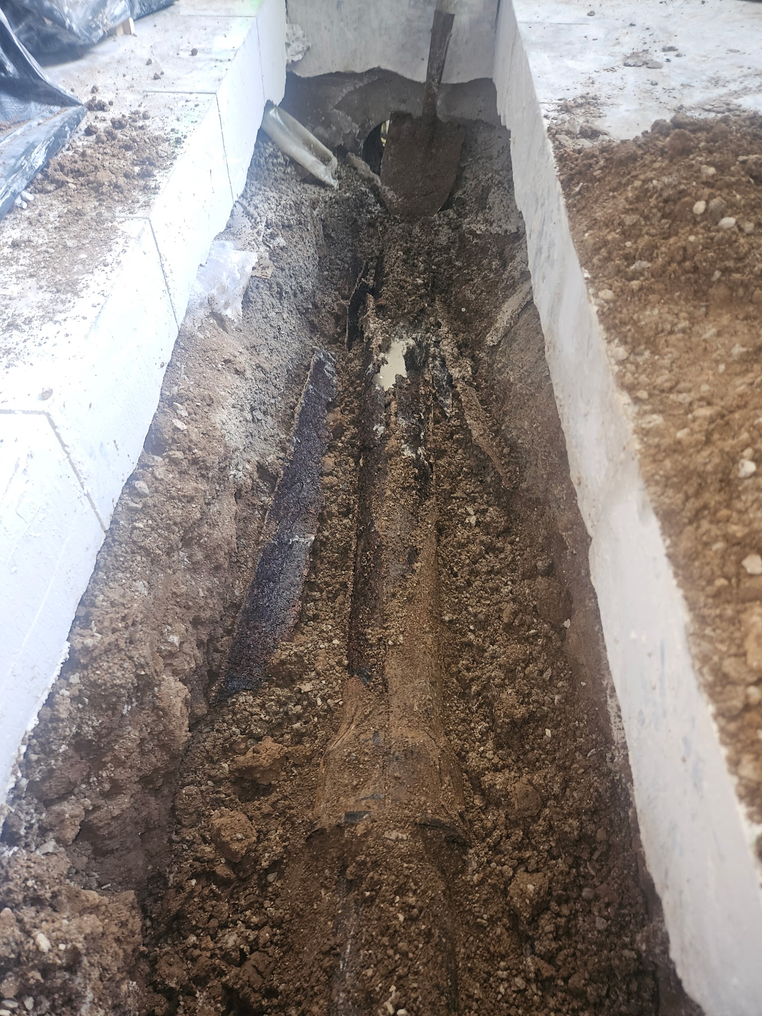 Rusted and collapsed drain pipe exposed beneath a concrete floor